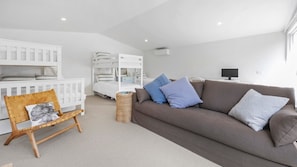 A modern living room with a brown sofa, a white crib, and a wicker chair. - Casa Della Nonna - Capel Sound (Capel Sound)