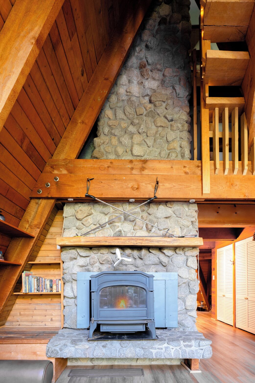 Una chimenea de piedra con puerta de vidrio azul, vigas de madera y pared de piedra.