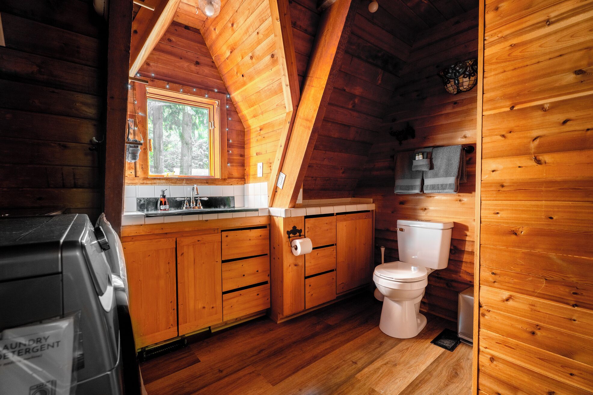 A wooden cabin interior with a kitchen area, including a sink, cabinets, and a toilet.