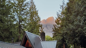 Eine Holzhütte mit Whirlpool und einer Terrasse mit Blick auf einen bewaldeten Bereich und einen Berg.