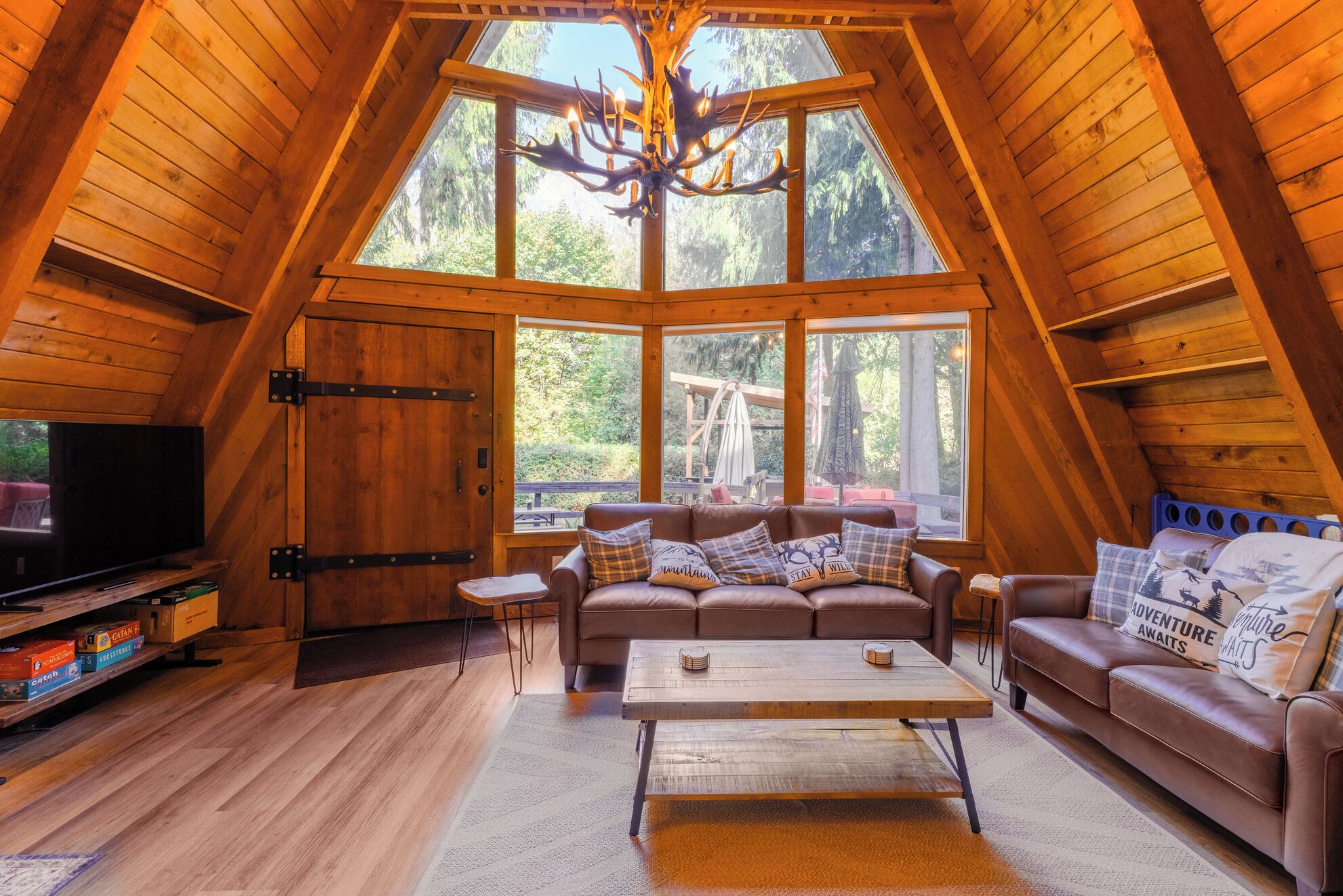 Una stanza accogliente in stile loft, con un'ampia finestra, soffitto in legno e televisione a sinistra.