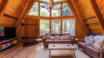 Una stanza accogliente in stile loft, con un'ampia finestra, soffitto in legno e televisione a sinistra.