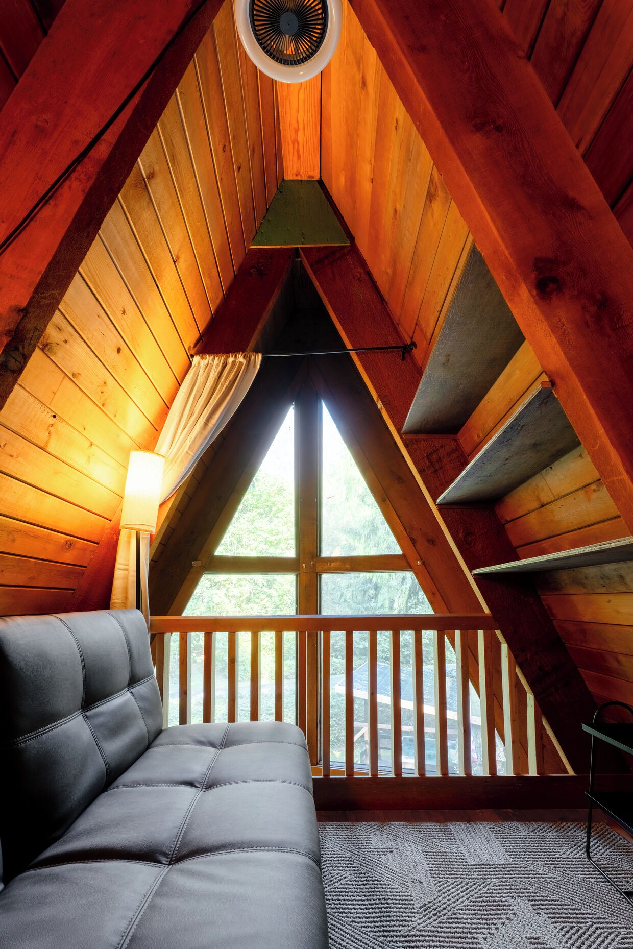 A cozy attic bedroom with a sloped ceiling, a bed, a window, and a fan.