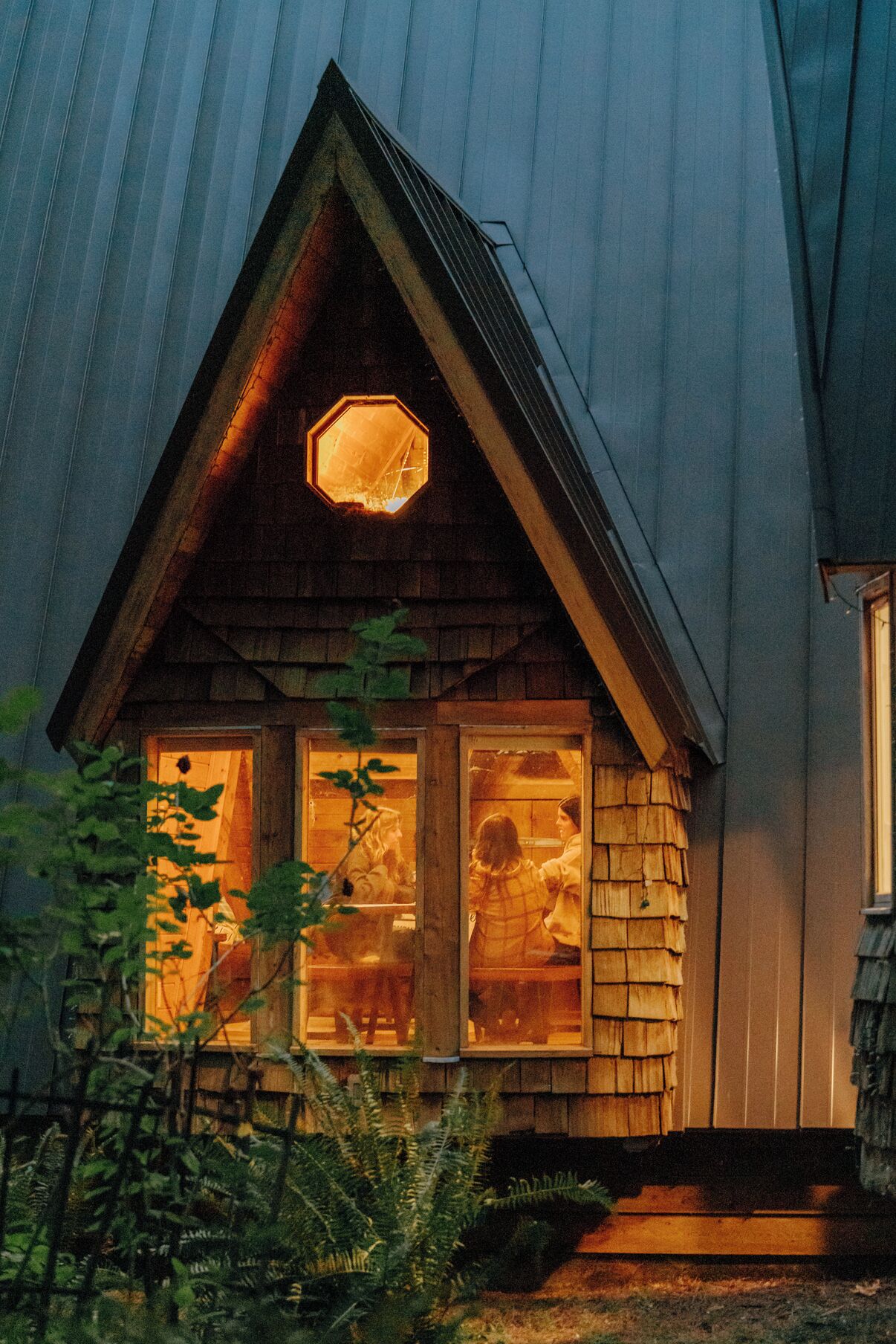 A wooden cabin with a triangular roof and a hexagonal window.