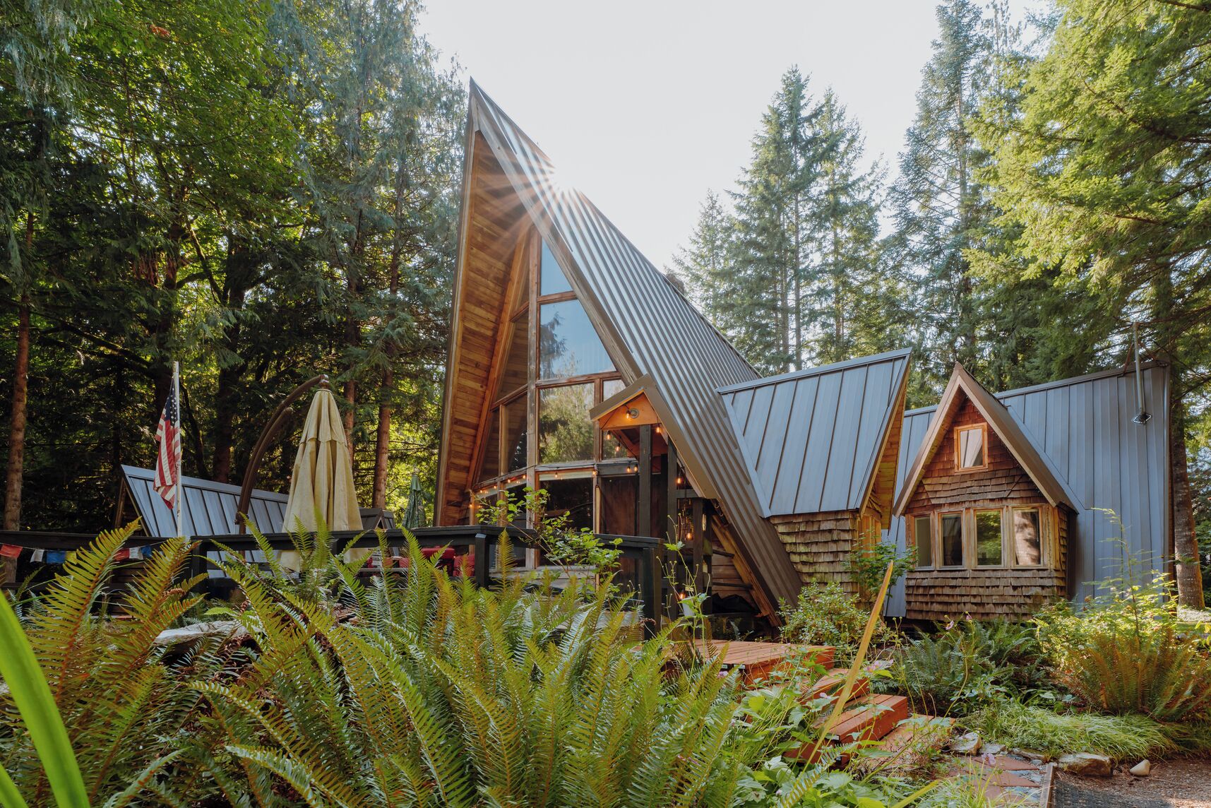 A cabin with a sloped roof, surrounded by dense forest.