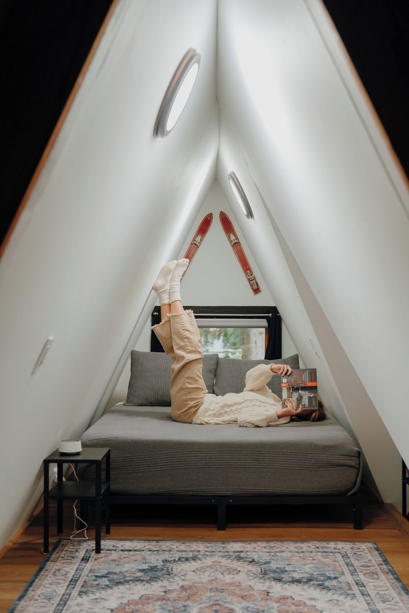 Una stanza triangolare con un letto, un tavolino e una sedia.