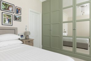 Un dormitorio con un armario grande, una mesita de noche con lámpara y fotografías enmarcadas en la pared.