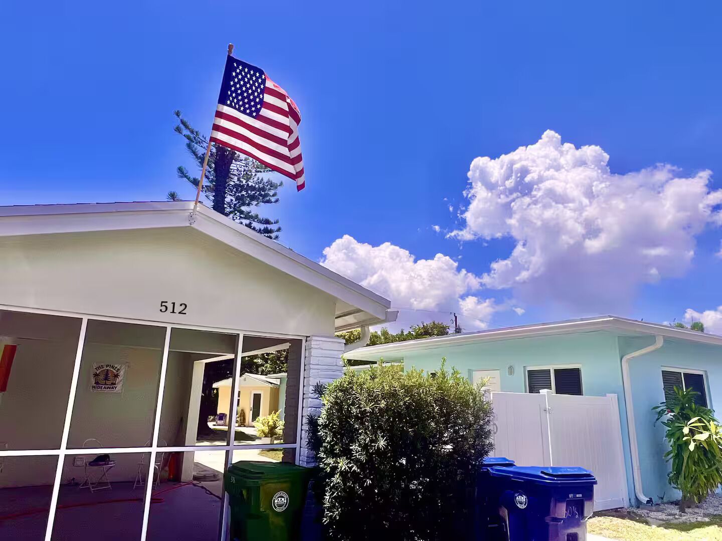 A residential building with an American flag on top, a visible address number 512, and a clear blue sky with clouds.