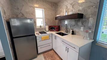 A modern kitchen with marble backsplash, stainless steel appliances, and a window providing natural light.