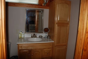 Une salle de bain avec un meuble-lavabo en bois, un évier, un miroir et un flacon de savon pour les mains.
