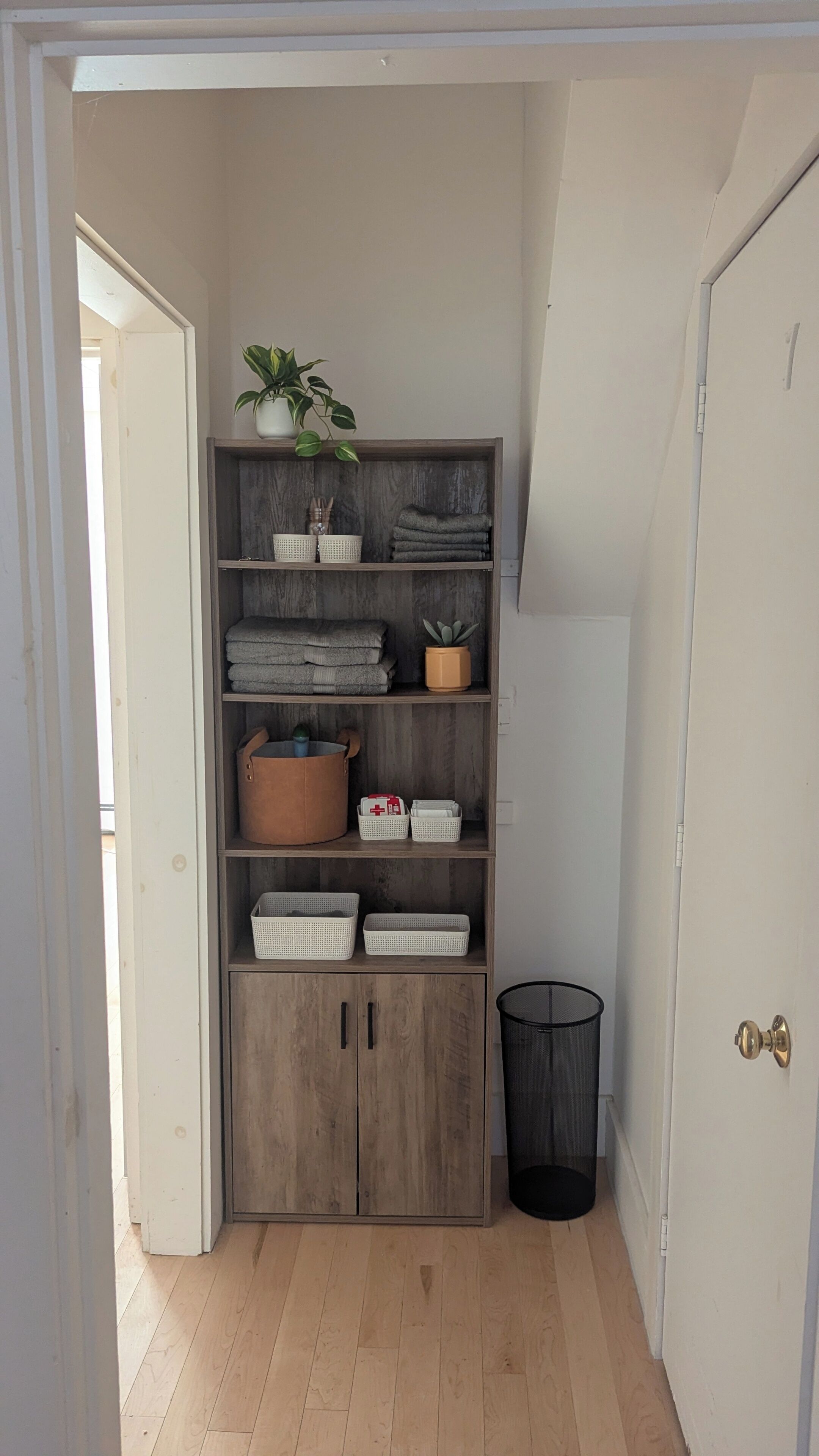 A wooden storage unit with shelves, baskets, and a plant.