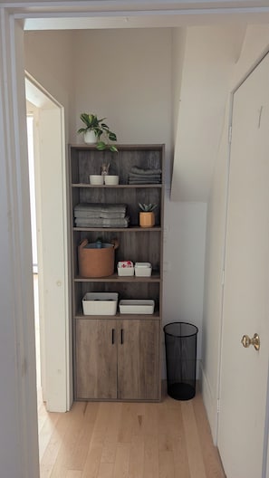 A wooden storage unit with shelves, baskets, and a plant.