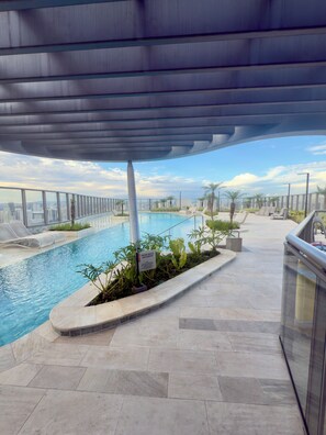 A rooftop pool with a clear view of the cityscape, surrounded by lounge chairs and potted plants. - Air Brooklin Residence (São Paulo)