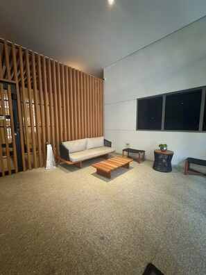 A modern living room with a sectional sofa, a wooden coffee table, a small side table, and a potted plant. - Air Brooklin Residence (São Paulo)