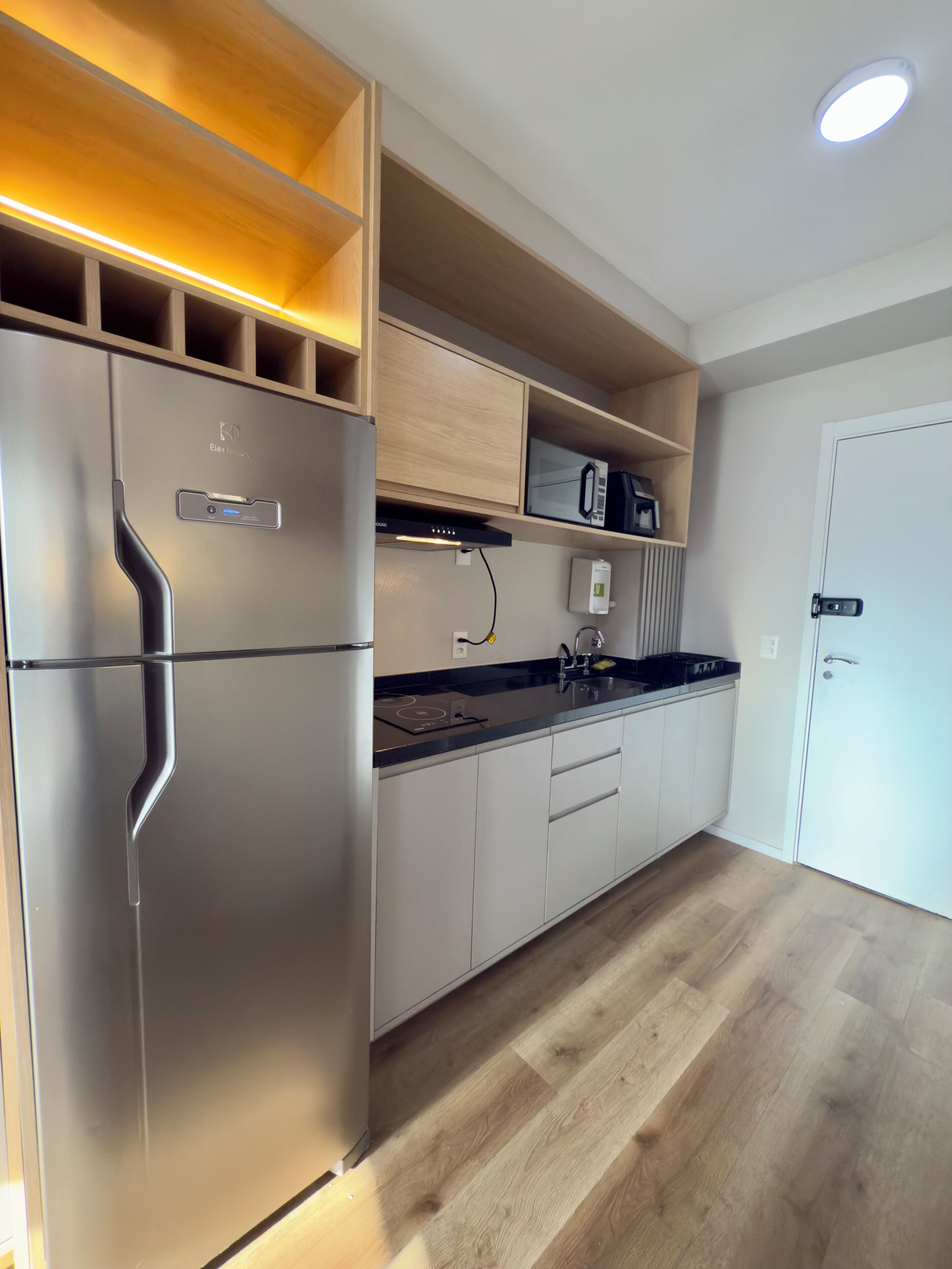 Une cuisine moderne dotée d’appareils électroménagers intégrés, de meubles de rangement en bois et d’un plan de travail.