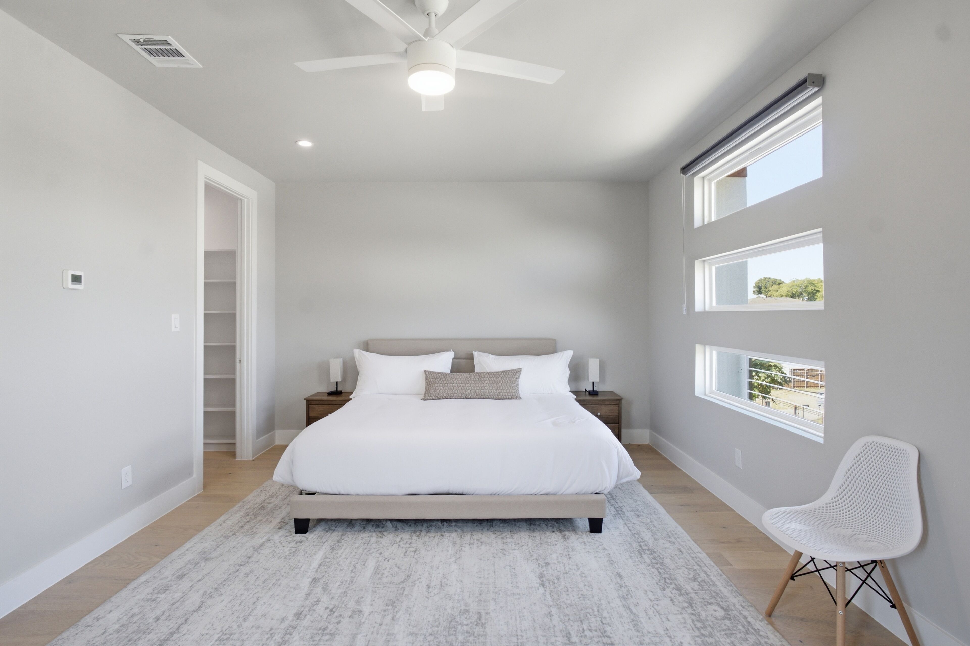 A bedroom with a bed, bedside tables, a chair, and a ceiling fan.
