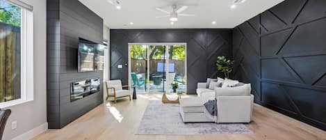 A modern living room with a sofa, a coffee table, and a TV mounted on the wall.