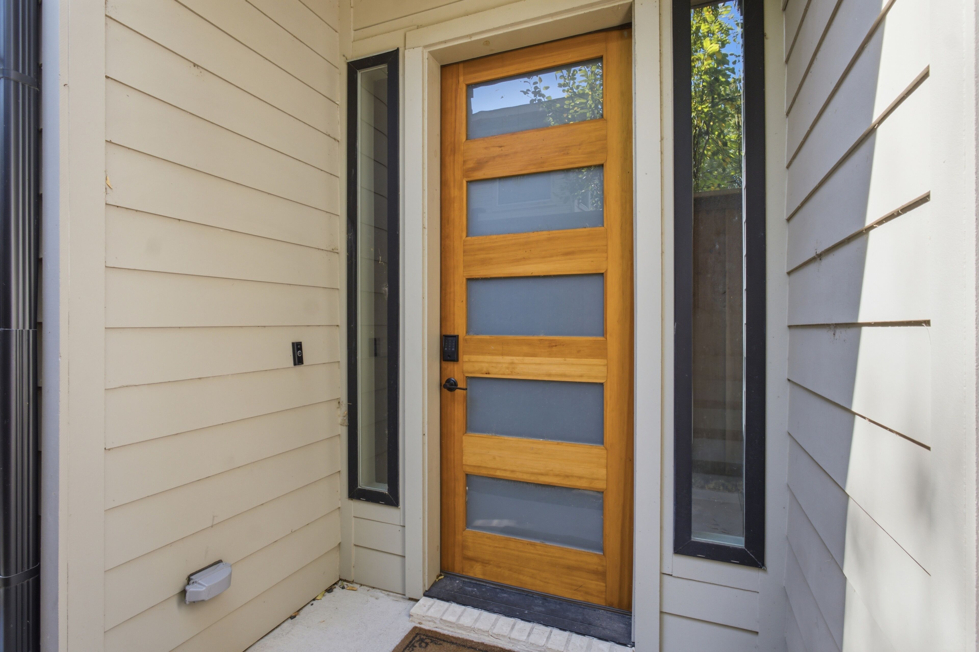 A wooden door with a glass panel, a mailbox, and a small step leading to the entrance.