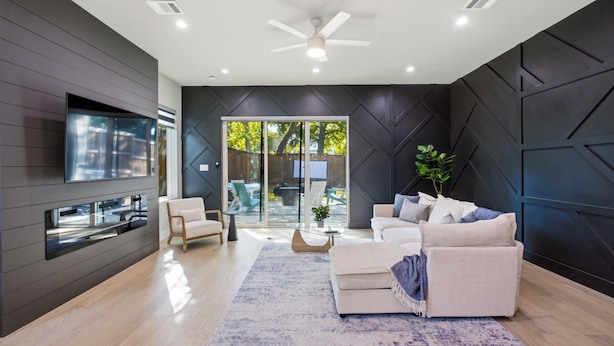A modern living room with a sofa, a coffee table, and a TV mounted on the wall. - Dallas LUXE 4BR, 4 Kings, Hot Tub, Outdoor Theater (Dallas)