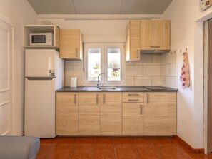 Eine kompakte Küche mit Holzausstattung, einer eingebauten Mikrowelle und einem Fenster für natürliches Licht.