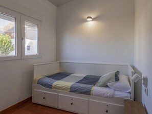 Ein Schlafzimmer mit einem Bett, einem Fenster und einer Wandleuchte.