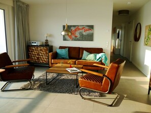A modern living room with a sofa, two armchairs, a coffee table, and a rug. - House Kiki, Apartment 2 "waikiki" (Heiligenhafen)