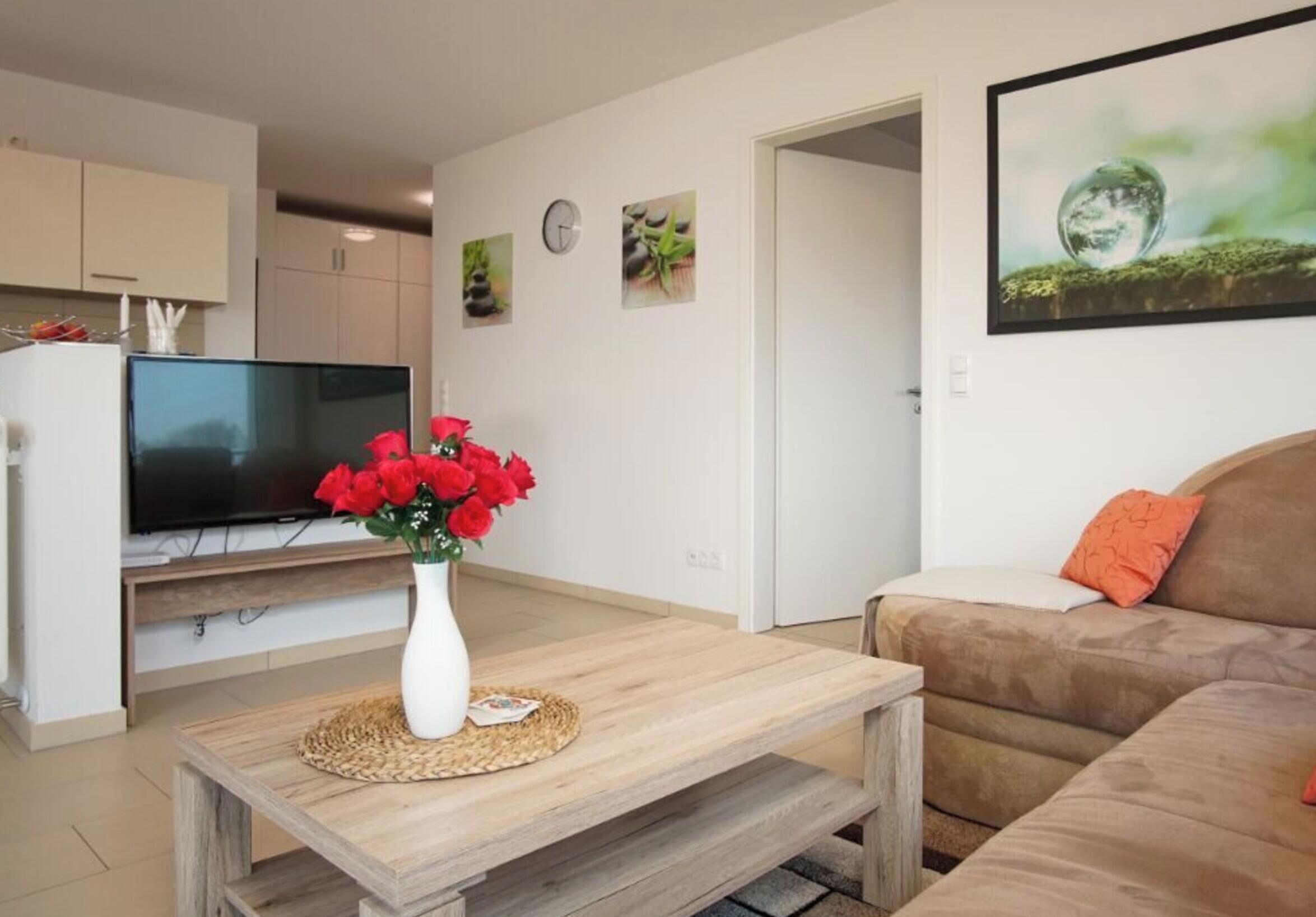 A living room with a wooden coffee table, a television, a sofa, and a painting on the wall.