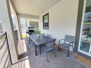 An outdoor patio with a table and chairs, a grill, and a view of a swimming pool. - Spacious 8-bedroom house in amazing Four Corners with AC (Four Corners)