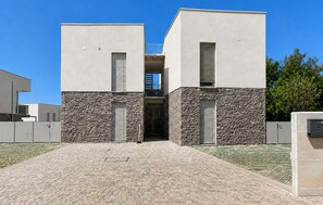 Ein modernes Gebäude mit einer Steinfassade, zwei großen Türen und blauem Himmel.