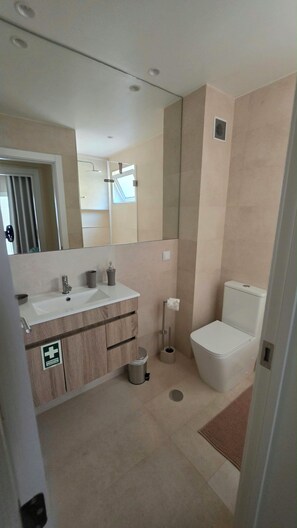 Ein modernes Badezimmer mit Waschbecken, Spiegel, Toilette und Dusche.