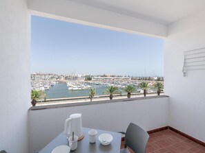 Ein Balkon mit Blick auf eine Marina, ein Tisch mit einem Stuhl und eine weiße Wand.