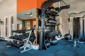 A gym with exercise equipment, including dumbbells, kettlebells, and a TRX suspension trainer. - Pool | Gym | Patio | Great For Mid/Long Stays (Mesa)