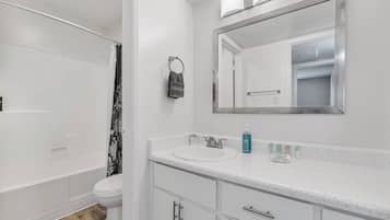 A bathroom with a white sink, mirror, and toilet.
