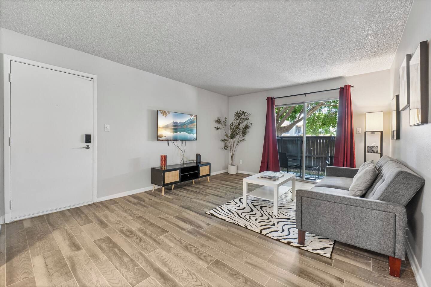 A living room with a sofa, a coffee table, a TV, and a plant.