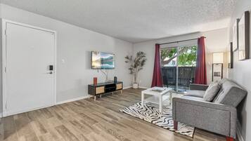 A living room with a sofa, a coffee table, a TV, and a plant.