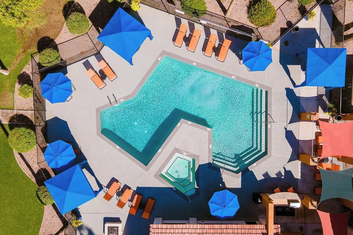 A swimming pool with sun loungers and umbrellas, surrounded by a landscaped area.