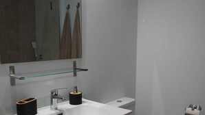Ein modernes Badezimmer mit einem weißen Waschbecken, einem Spiegel und einer Toilette.