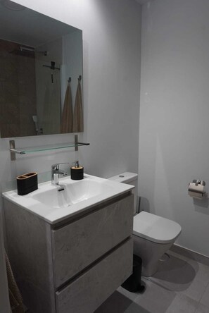 Un baño moderno con un lavamanos blanco, un espejo y un inodoro.