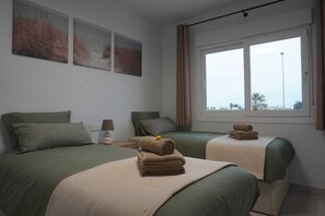 Una habitación de hotel con dos camas, un ventanal con vistas y obras de arte en la pared.