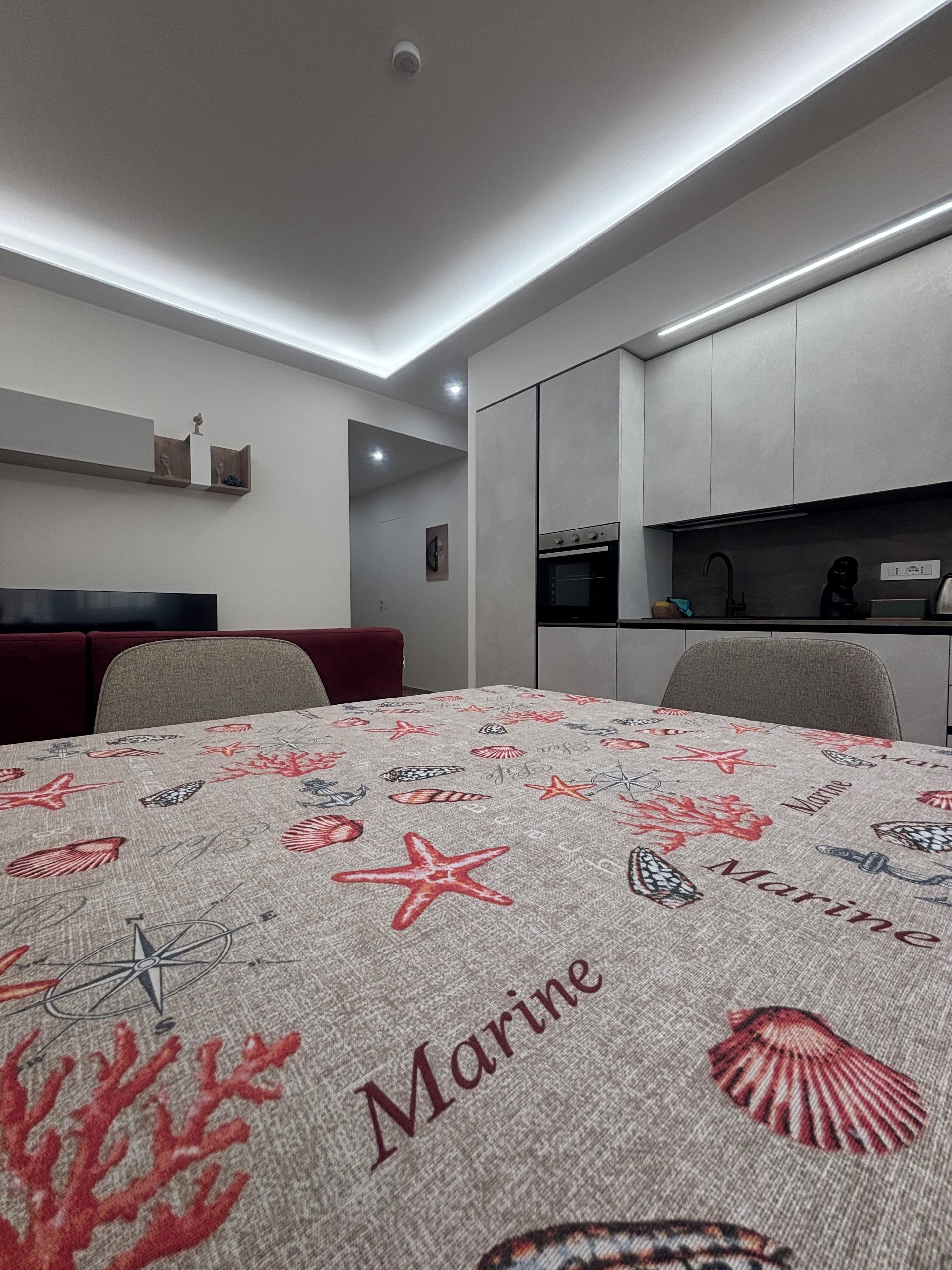A modern kitchen with built-in appliances and a dining area with a marine-themed tablecloth.