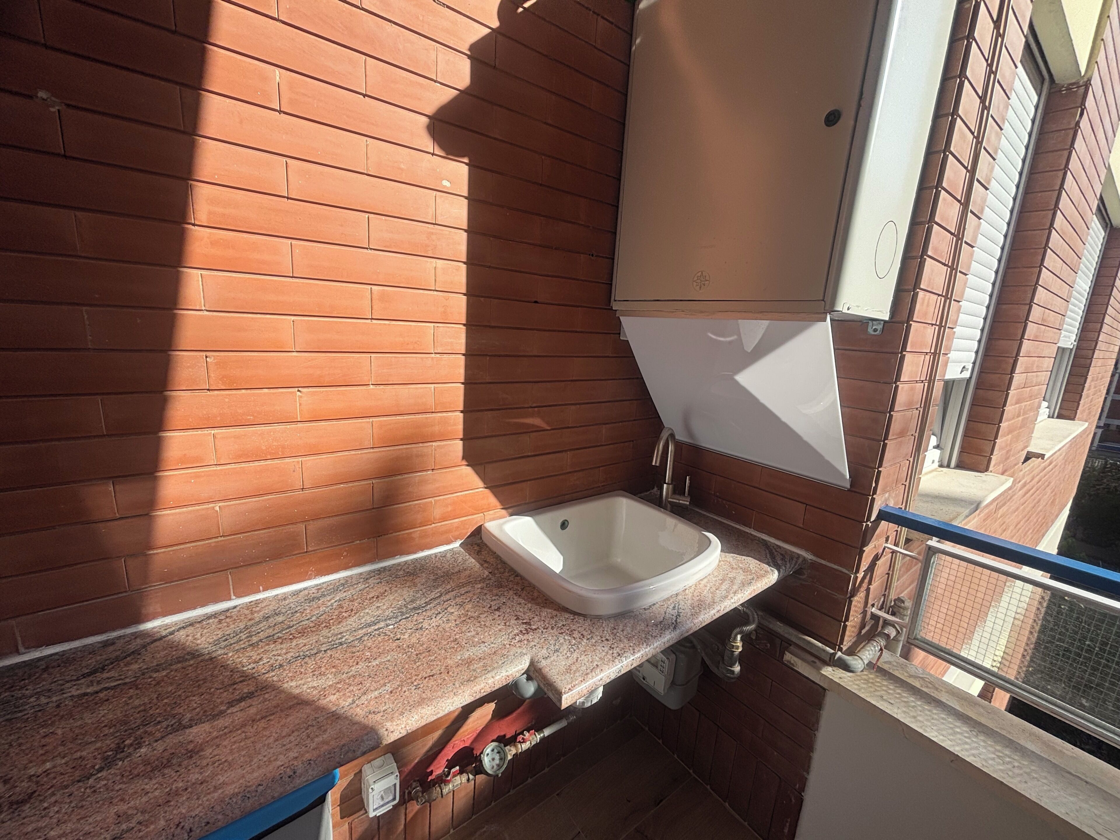 Een badkamer met een granieten aanrechtblad, een witte wasbak en een zichtbare waterleiding.