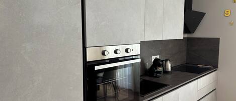 Une cuisine moderne dotée d’un four encastré, d’une plaque de cuisson et d’un plan de travail noir.