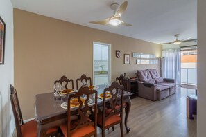 A dining area with a table set for four, a sofa, and a ceiling fan. - 2BR Apt Just 10 Mins From Barra da Tijuca Beach Vlm905 (Rio de Janeiro)