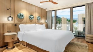 Ein Hotelzimmer mit einem großen Bett, Holzwandverkleidung, Blick auf die Stadt und einem Deckenventilator.