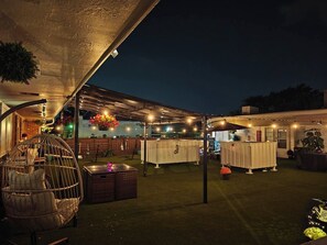 An outdoor patio area with a covered seating area, a pool table, and a bar area.