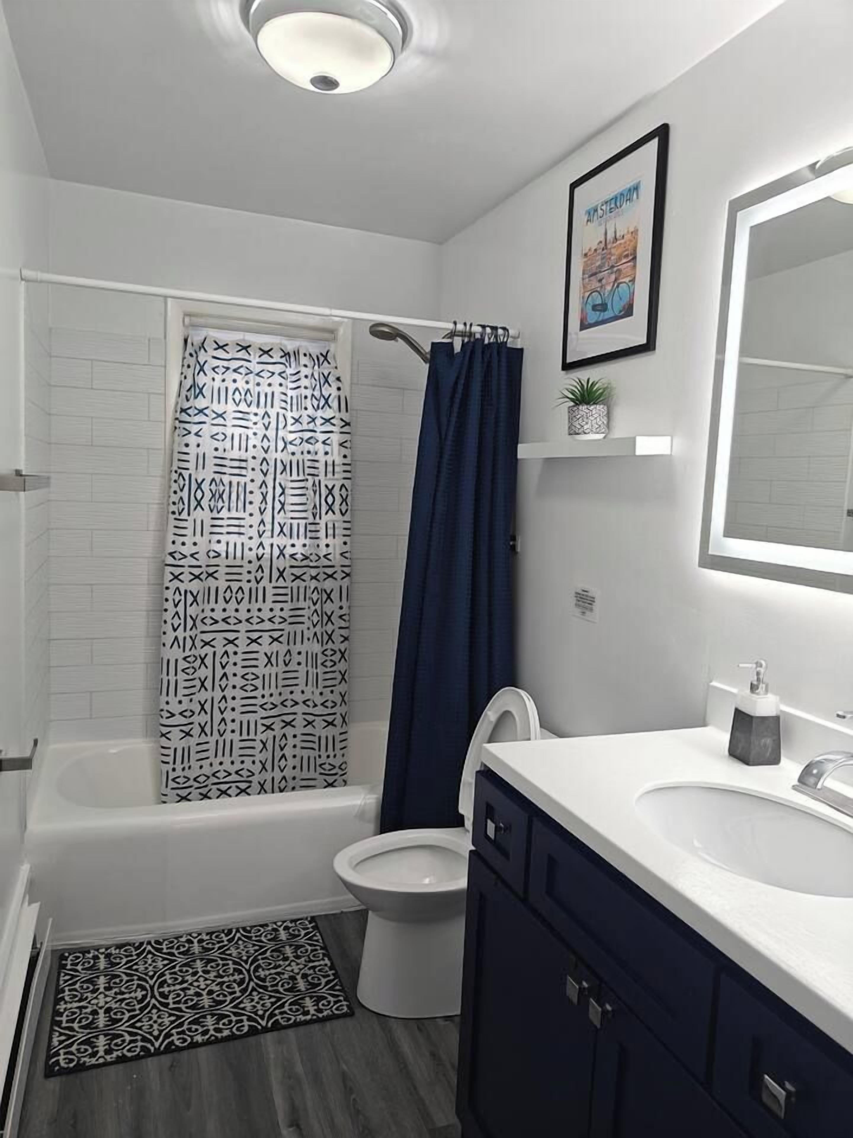 A modern bathroom with a white bathtub, a toilet, a sink, and a shower curtain.