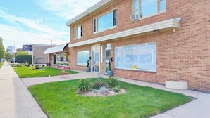 A two-story brick building with a flat roof, large windows, and a covered entrance. - Greenwood Loft & Rooftop (Waukegan)