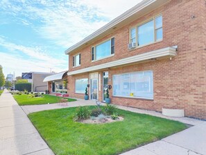 A two-story brick building with a flat roof, large windows, and a covered entrance. - Greenwood Loft & Rooftop (Waukegan)