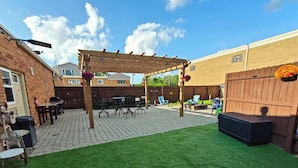 A backyard with a pergola, patio furniture, and a well-maintained lawn. - Greenwood Loft & Rooftop (Waukegan)
