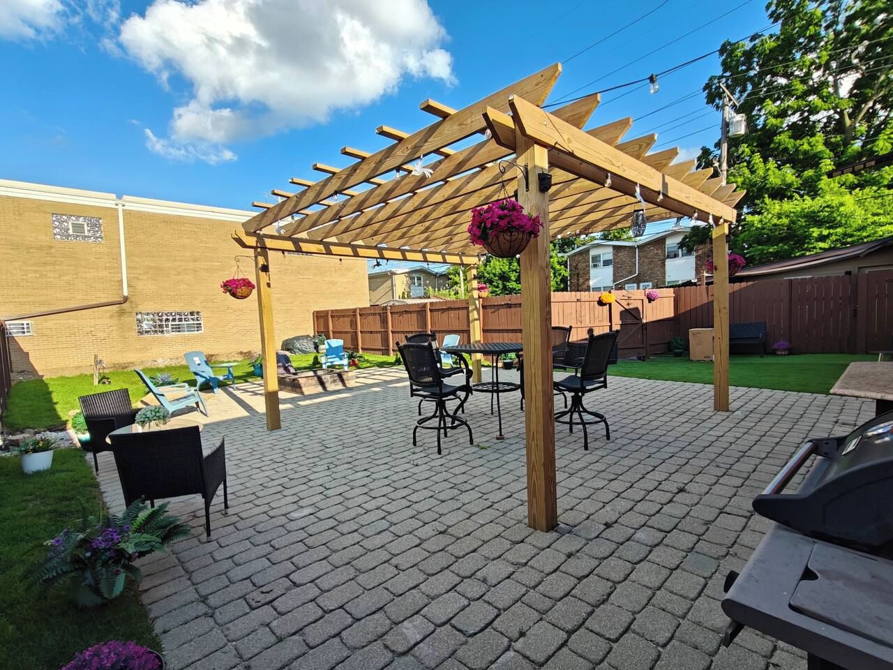 Un espace patio agrémenté d’une pergola, de sièges d’extérieur et d’un sol en briques.